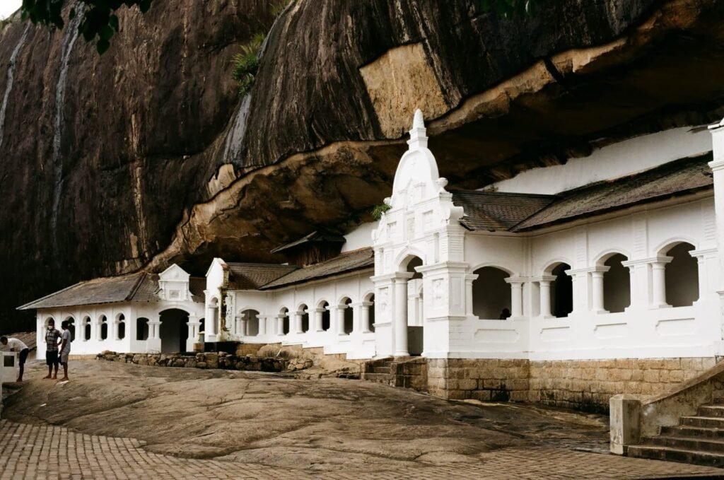 Historic white Dambulla Cave Temple under rock cliff Sri Lanka